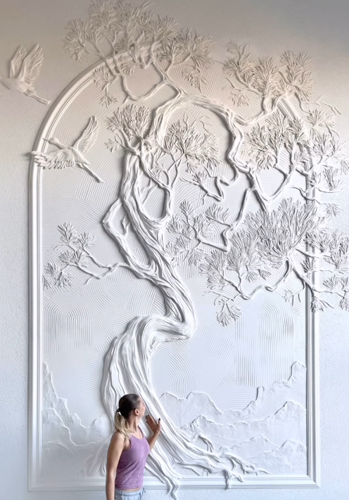 Large white sculptural wall relief depicting a tree with flowing roots and branches, integrated into an architectural space.